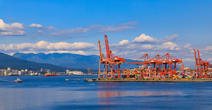 Vancouver harbour with red gantry cranes and cargo shipping containers at the Centerm terminal on the waterfront, Canada